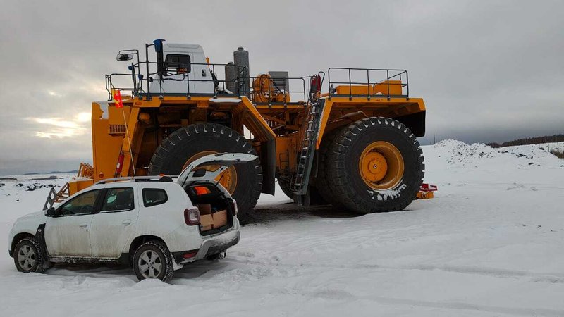 Карьерный погрузчик и автомобиль службы связи на заснеженном разрезе